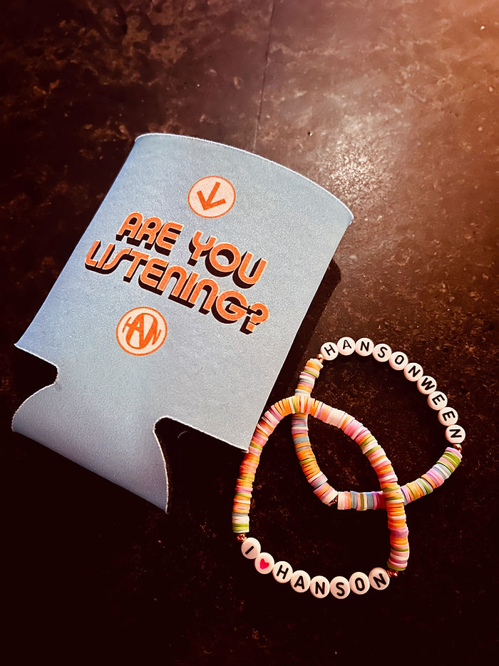 A photo of a Hanson drink koozie that says "Are You Listening" and two beaded bracelets that say I *heart* Hanson and Hansonween